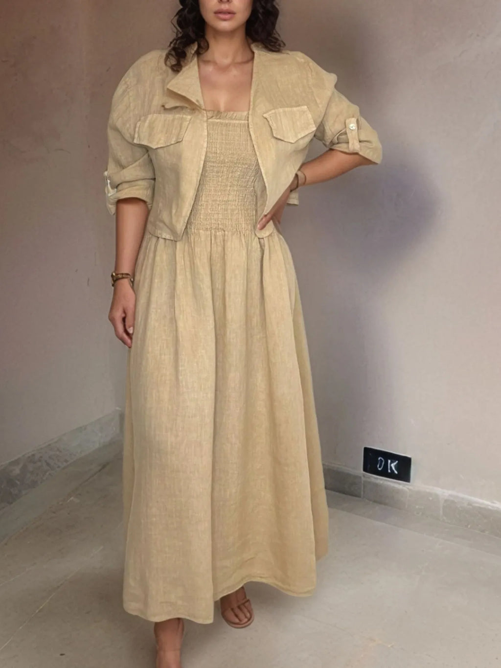 Woman wearing a beige dress and jacket in an indoor setting